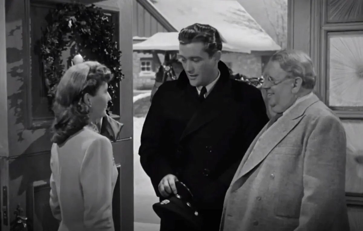 (L–R) Elizabeth Lane (Barbara Stanwyck) greets Jefferson Jones (Dennis Morgan) while her uncle Felix (S.Z. Sakall) watches in “Christmas in Connecticut.” (Warner Bros.)