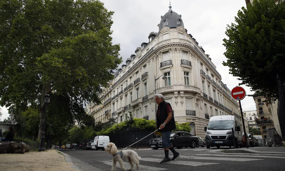 A man walks his dog next to an apartment building owned by Jeffrey Epstein in Paris on Aug.13, 2019. (Francois Mori/AP Photo)