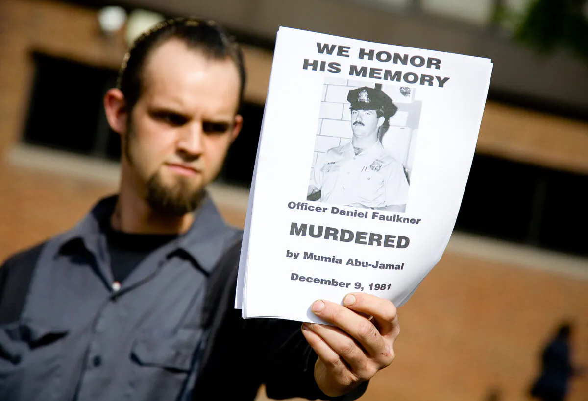 A counter-protester holds a handbill in remembrance of slain police officer Daniel Faulkner at a rally for Faulker's convicted murderer, death-row inmate Mumia Abu-Jamal outside the Federal Court building in Philadelphia, on May 17, 2007. (Jeff Fusco/Getty Images)