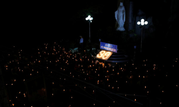 Catholic believers hold lit candles during a mass prayer for 39 Vietnamese