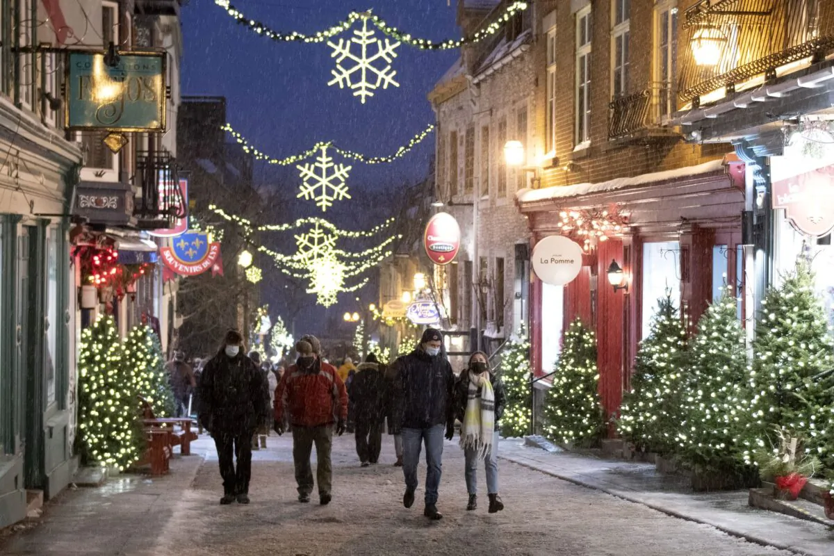 People walk along a street festooned with Christmas decorations in the Petit Champlain district of Quebec City on Dec. 20, 2020. (The Canadian Press/Jacques Boissinot)