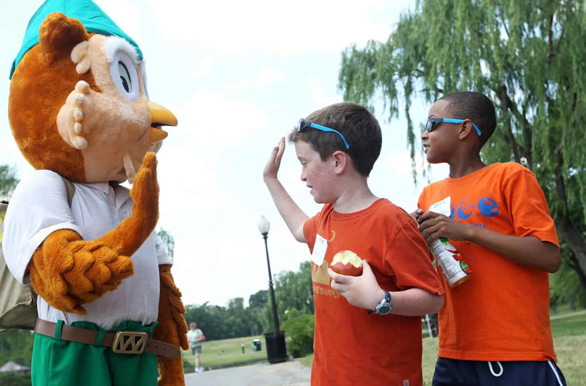 Child hi-fives the icon of U.S. Forest Service, Woodsy the Owl (L), at the Constitution Gardens Pond of the National Mall in Washington on June 6, 2011. (Alex Wong/Getty Images)