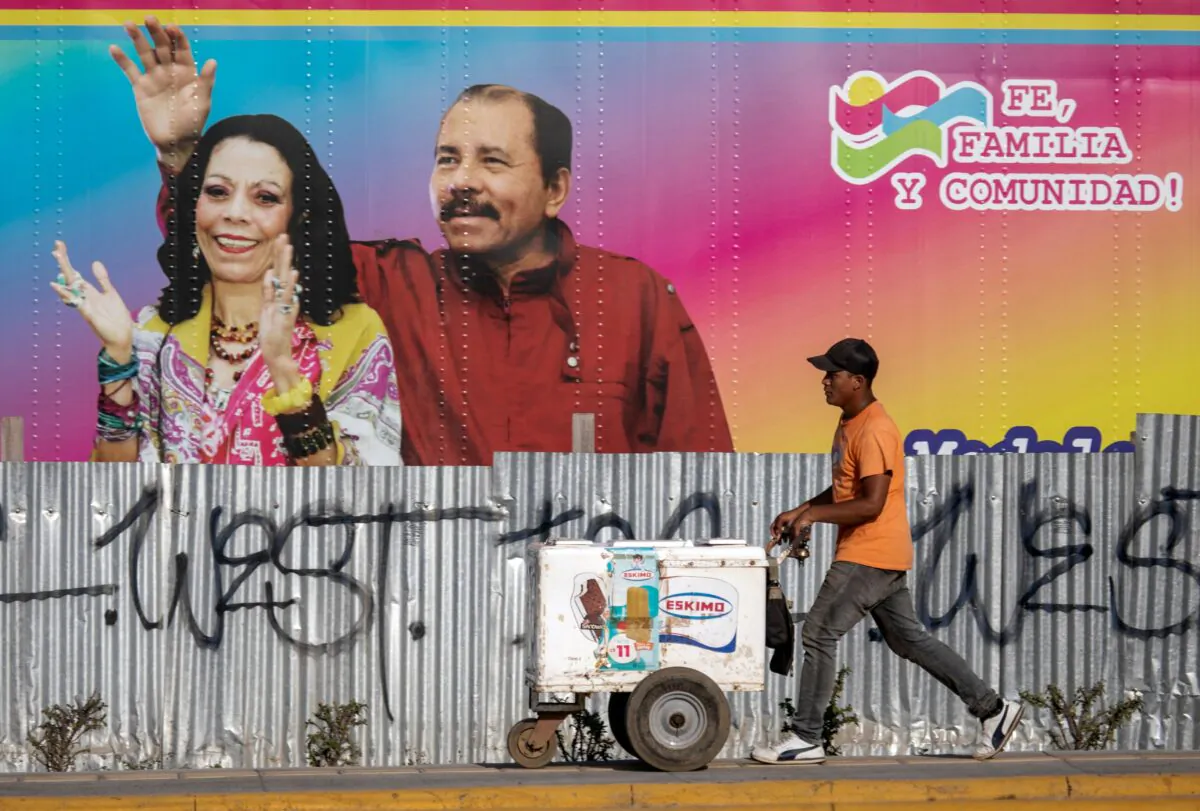 An ice cream vendor walks by a mobile health clinic displaying a picture of Nicaragua's President Daniel Ortega (R) and his wife Vice President Rosario Murillo (R) in Managua on April 14, 2020. (INTI OCON/AFP via Getty Images)