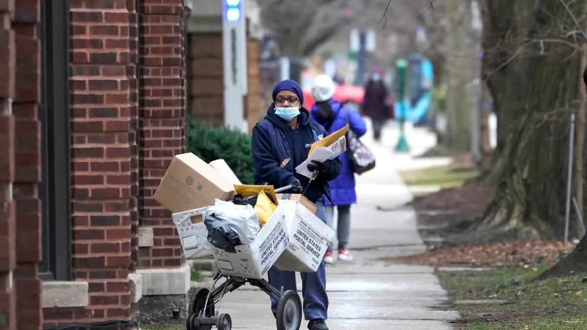 A U.S. postal worker delivers packages, boxes, and letters Tuesday along her route in the Hyde Park neighborhood of Chicago, Dec. 22, 2020, just three days before Christmas. (Charles Rex Arbogast/AP Photo)