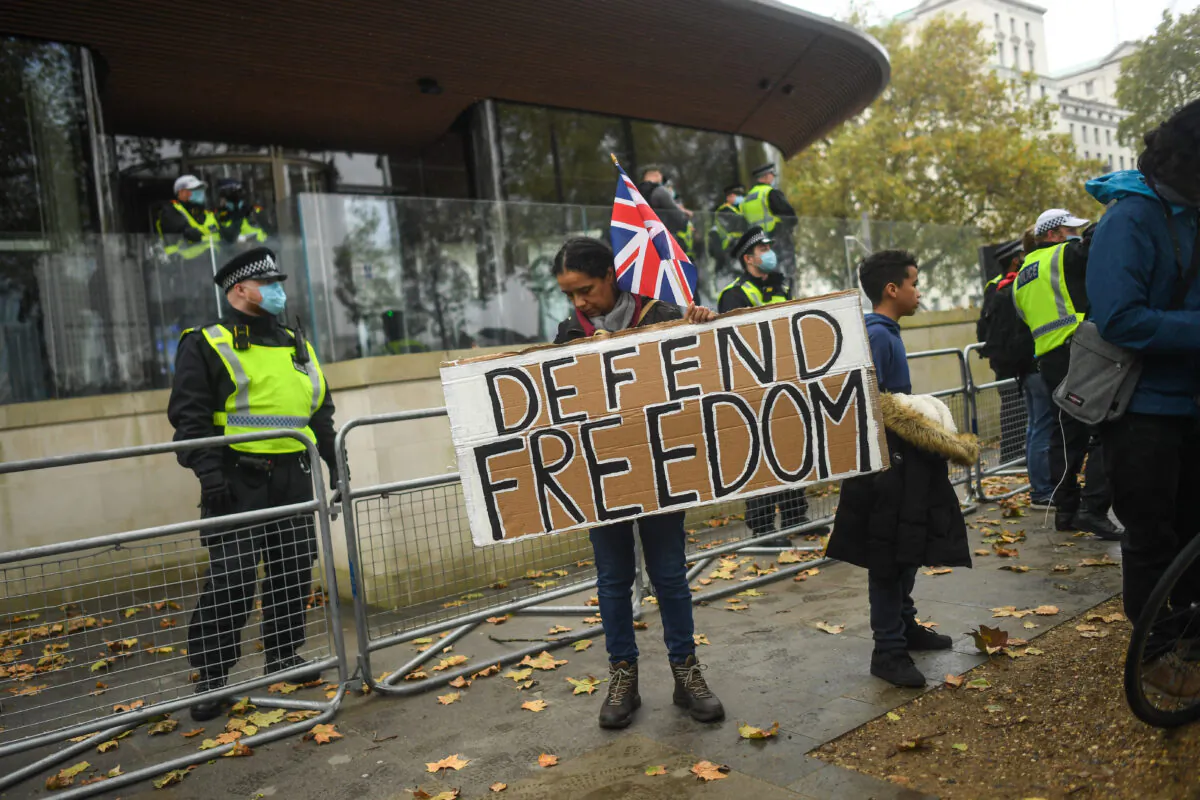 A protester holds a sign reading 'Defend Freedom' during a Unite for Freedom march outside New Scotland Yard on Oct. 24, 2020, in London. Hundreds of anti-mask and anti-lockdown protesters marched through central London demonstrating against latest coronavirus lockdown measures. (Photo by Peter Summers/Getty Images)