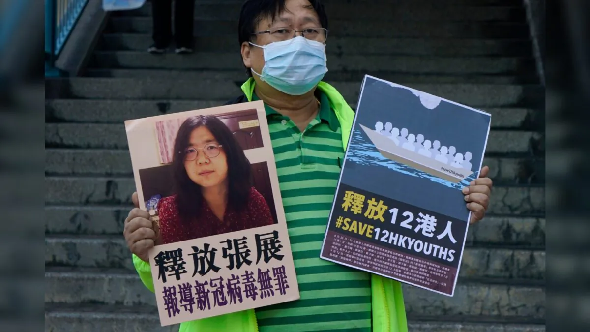 A pro-democracy activist holds placards with the picture of former lawyer Zhang Zhan outside the Chinese central government's liaison office, in Hong Kong, on Dec. 28, 2020. (Kin Cheung/AP Photo)