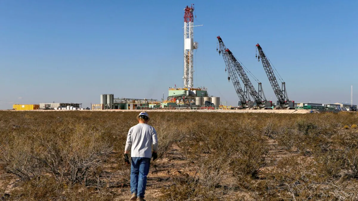 An oil worker walks toward a drill rig after placing ground monitoring equipment in the vicinity of the underground horizontal drill in Loving County, Texas, on Nov. 22, 2019. (Angus Mordant/Reuters)