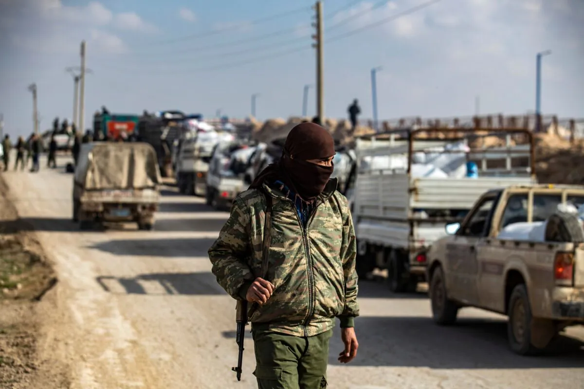 An internal security patrol member stands in front of a convoy of trucks transporting Syrian women and children suspected of being related to the ISIS terrorist group, at the Kurdish-run al-Hol camp, in the al-Hasakeh governorate in northeastern Syria, on Dec. 21, 2020. (Delil Souleiman/AFP via Getty Images)