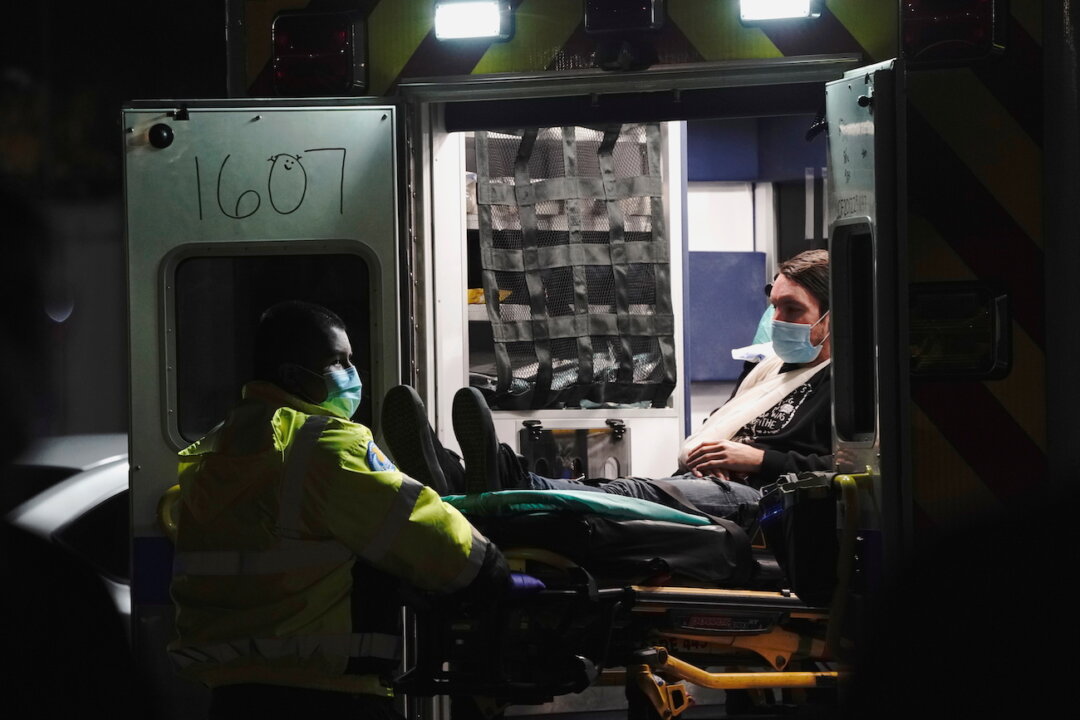 An emergency medical technician lowers a patient from an ambulance outside the emergency room at the Community Hospital of Huntington Park in Huntington Park, California, on Dec. 29, 2020. (Bing Guan/Reuters)