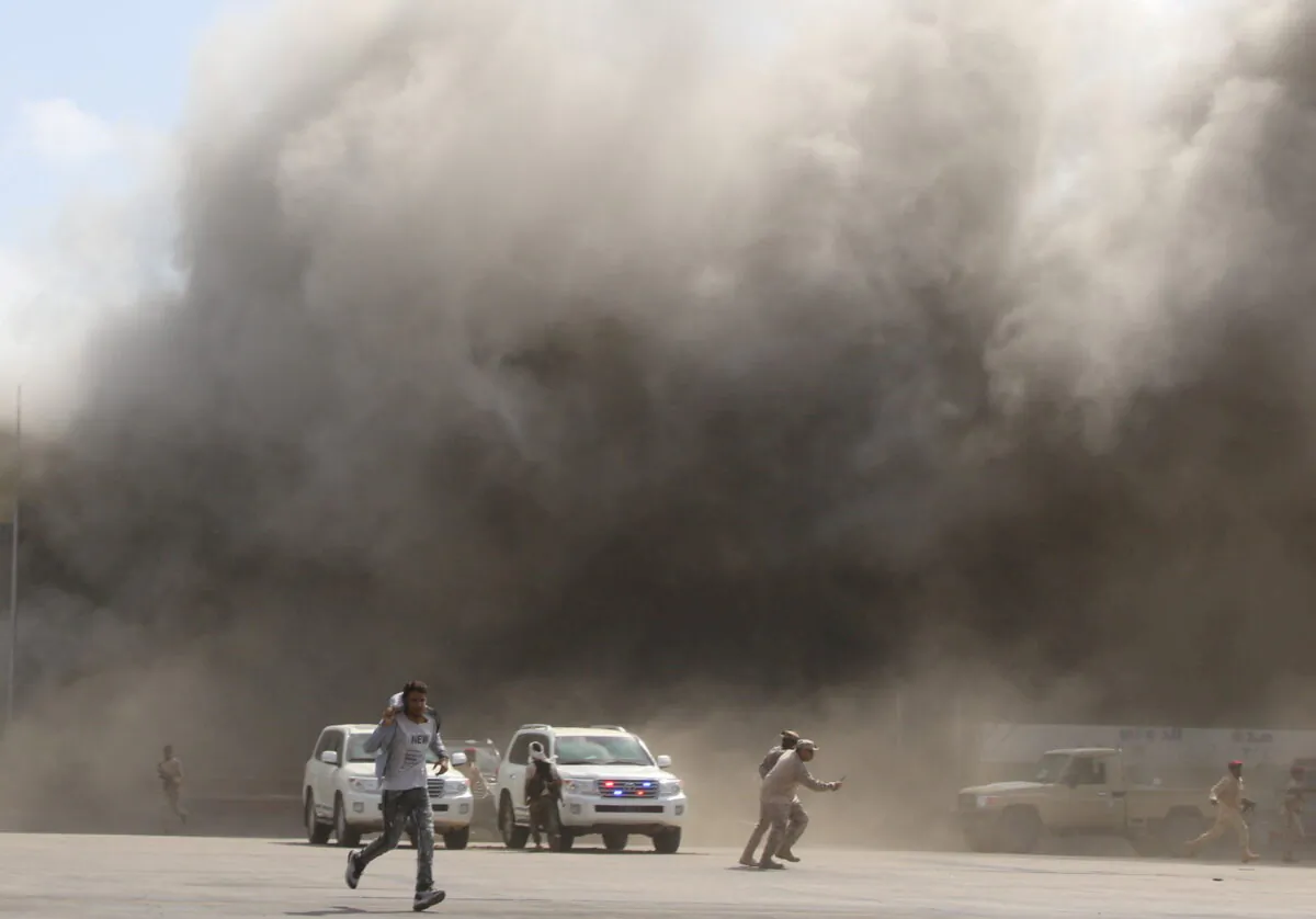 People react as dust rises after explosions hit Aden airport in Aden, Yemen, on Dec. 30, 2020. (Fawaz Salman/Reuters)