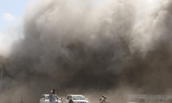 People react as dust rises after explosions hit Aden airport in Aden, Yemen, on Dec. 30, 2020. (Fawaz Salman/Reuters)