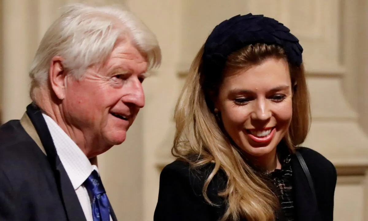 Stanley Johnson, the UK prime minister's father, and Carrie Symonds, partner of Prime Minister Boris Johnson, are seen in the Peers Lobby as they attend the Queen's Speech during the State Opening of Parliament in the Houses of Parliament in London on Oct. 14, 2019. (Tolga Akmen/Pool via Reuters)