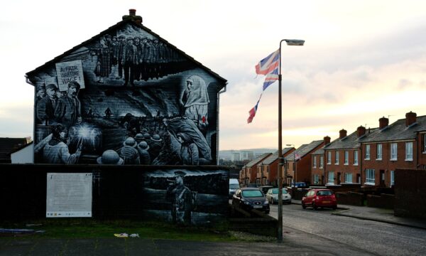 A tattered Union Jack flag hangs from a lamppost on a terraced street in Belfast