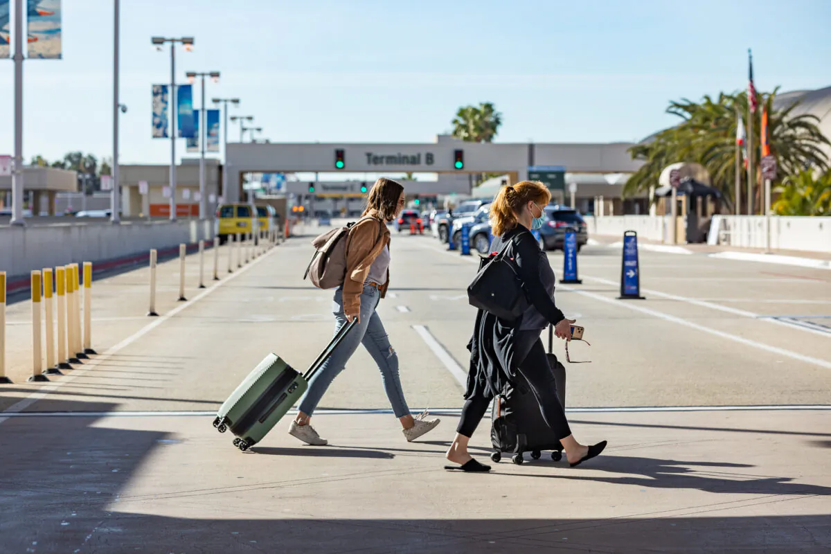 Travelers walk with thier baggage at John Wayne Airport, in Santa Ana, Calif., on Dec. 30, 2020. (John Fredricks/The Epoch Times)