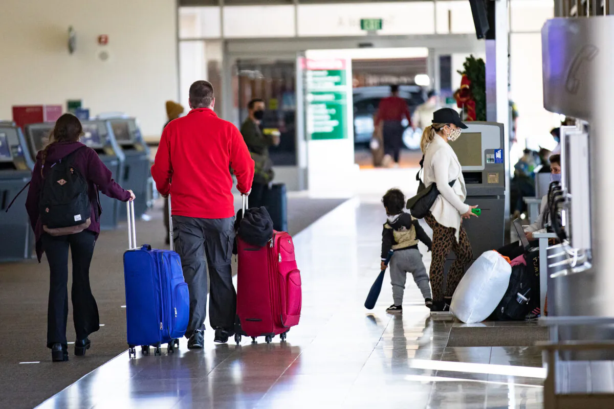 Travelers walk with their baggage at John Wayne Airport, in Santa Ana, Calif., on Dec. 30, 2020. (John Fredricks/The Epoch Times)