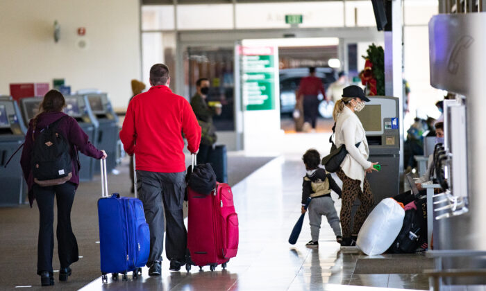 Travelers walk with thier baggage at John Wayne Airport, in Santa Ana, Calif., on Dec. 30, 2020. (John Fredricks/The Epoch Times)