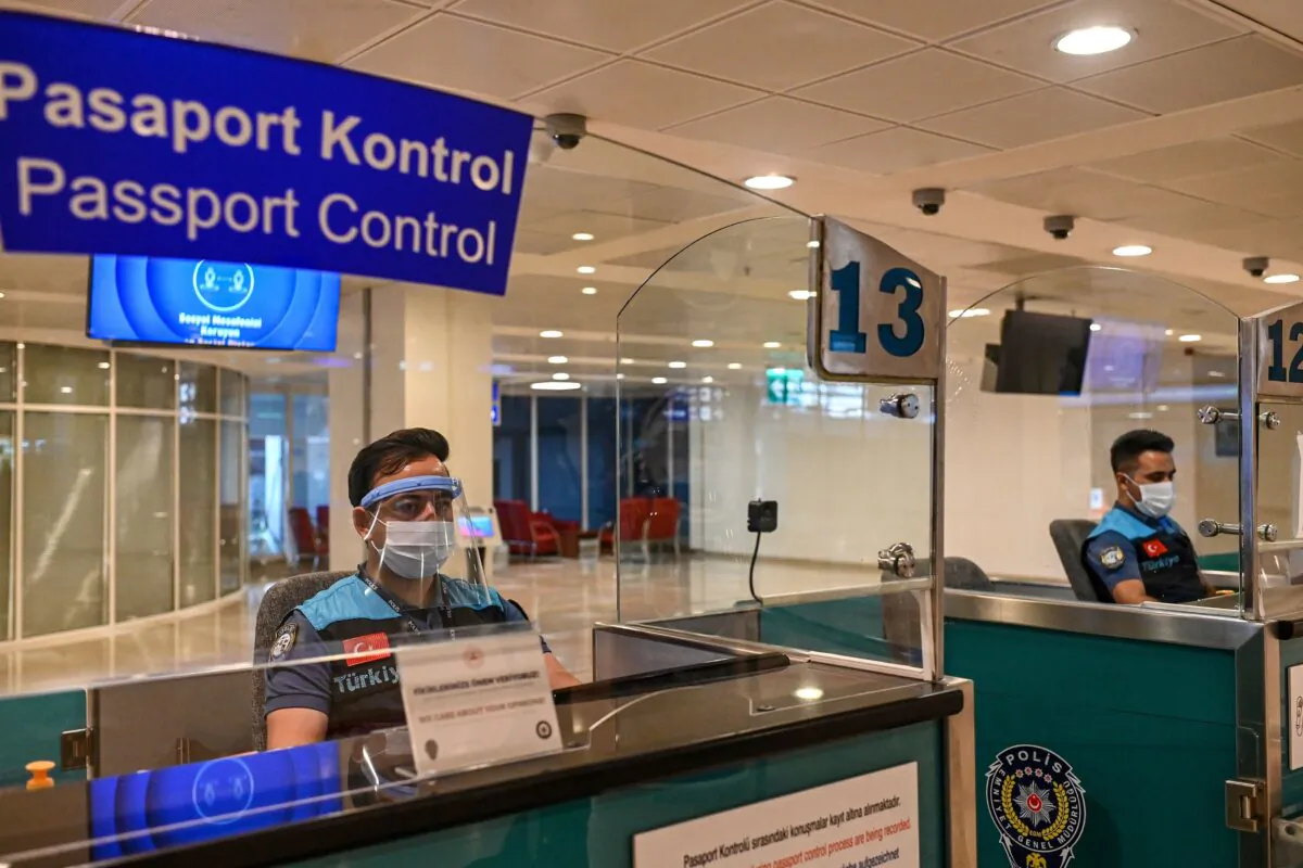 Turkish police officers wearing masks and visors wait for passengers at the passport control, at Antalya International airport in Antalya in southern Turkey on June 19, 2020. (Ozan Kose/AFP via Getty Images)