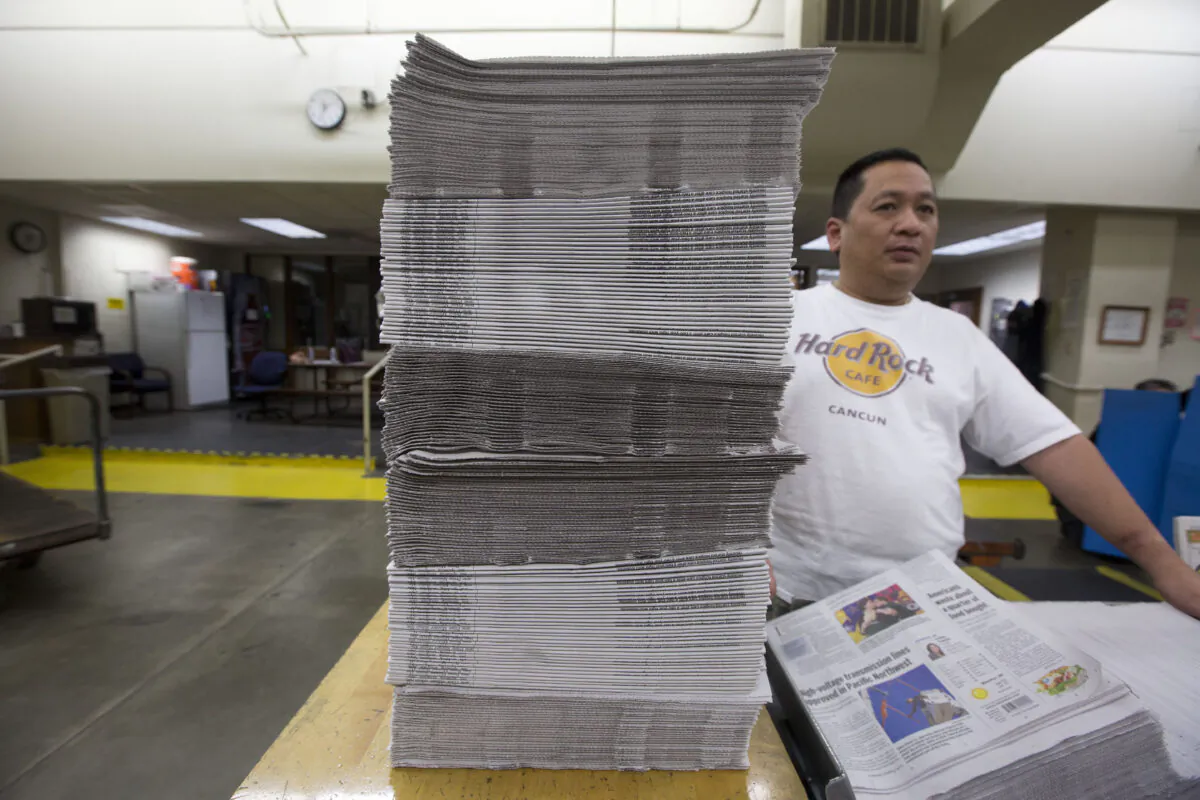 An employee bundles stacks of freshly printed newspapers at the Columbian newspaper in Vancouver, Wash., on April 18, 2018. (Natalie Behring/Getty Images)