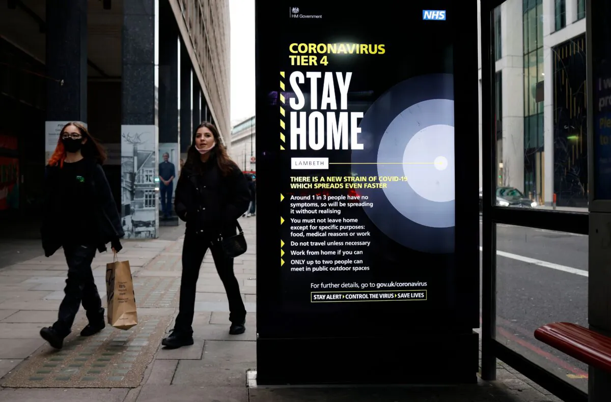 People, some wearing masks, walk past a bus stop with a government message about the CCP virus tier 4 restrictions urging people to stay home in London on Dec. 29, 2020. (Tolga Akmen/AFP via Getty Images)