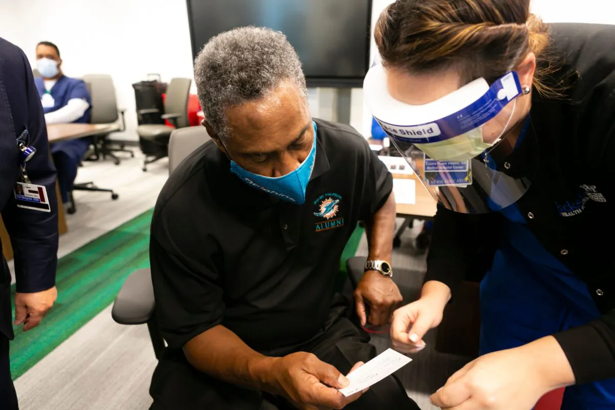 Nat Moore, 69, formerly of the Miami Dolphins, receives his vaccination card after getting his first dose of the Pfizer-BioNtech COVID-19 vaccine at the Christine E. Lynn Rehabilitation Center, in Miami, Fla., on Dec. 30, 2020. (Eva Marie Uzcategui/AFP via Getty Images)
