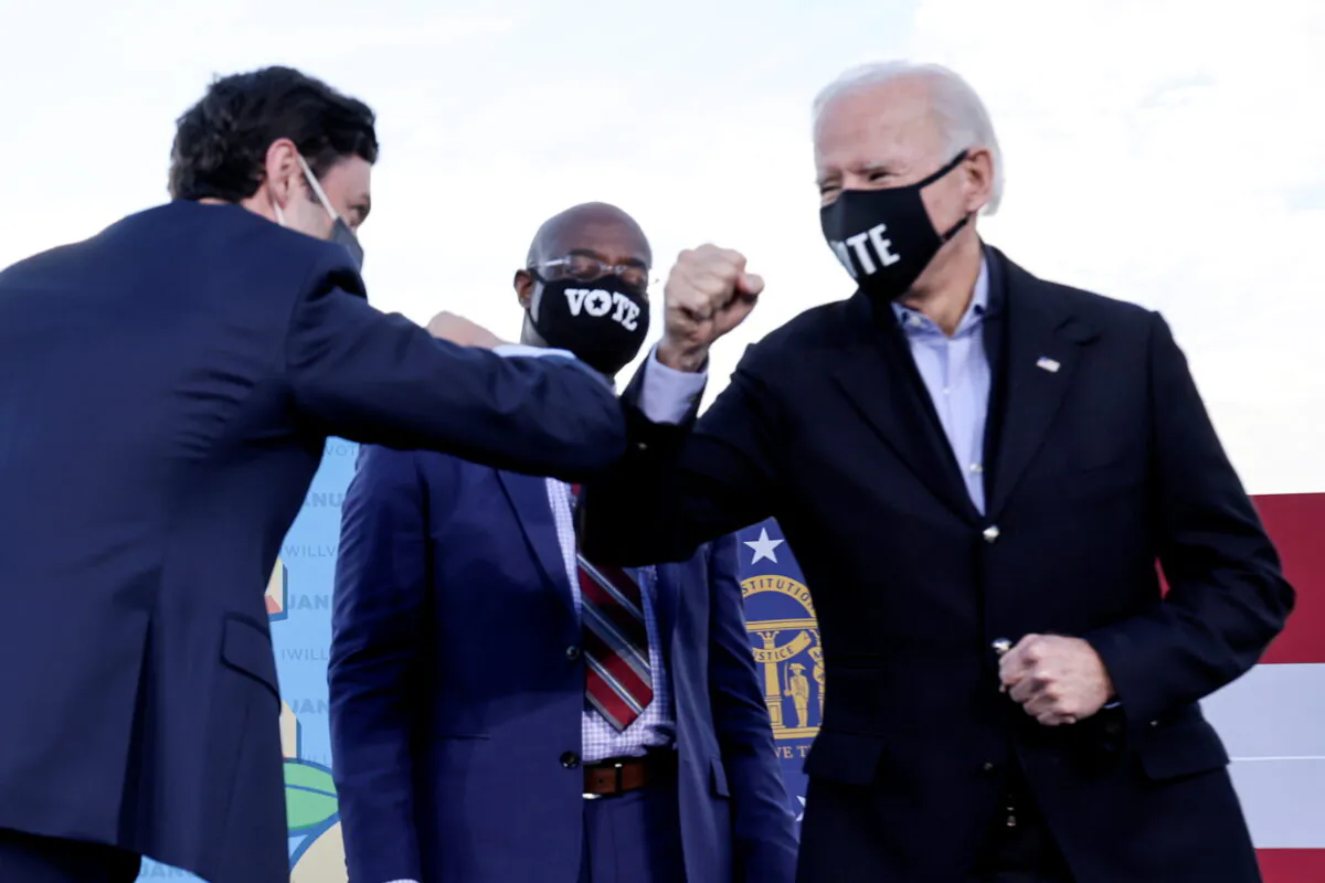 Democratic presidential nominee Joe Biden elbow bumps Democratic U.S. Senate candidate from Georgia Jon Ossoff, as fellow candidate Raphael Warnock looks on ahead of their Jan. 5 run-off elections, during a drive-in campaign rally in Atlanta, Ga., on Jan. 4, 2021. (Jonathan Ernst/Reuters)