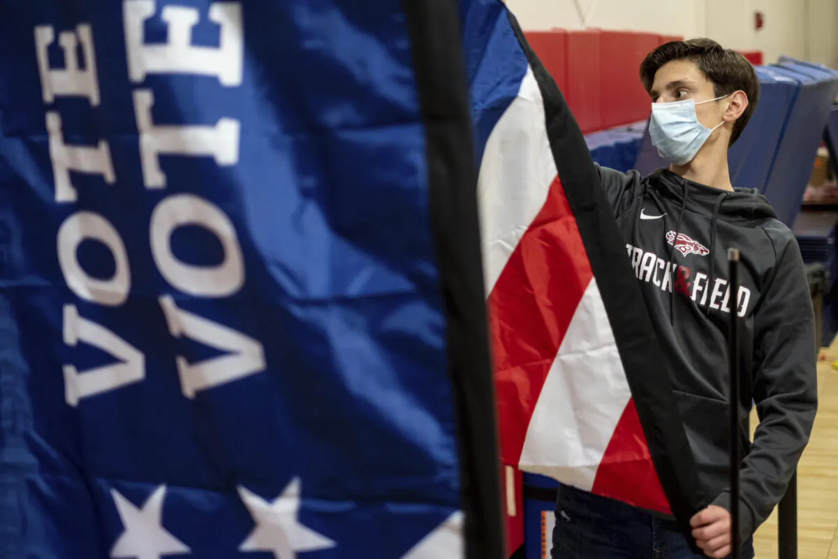 Thomas Hedrich sets up voting flags at a polling location in advance of the Senate runoff elections in Gwinnett County, Ga., on Jan. 4, 2021. (Ben Gray/AP Photo)