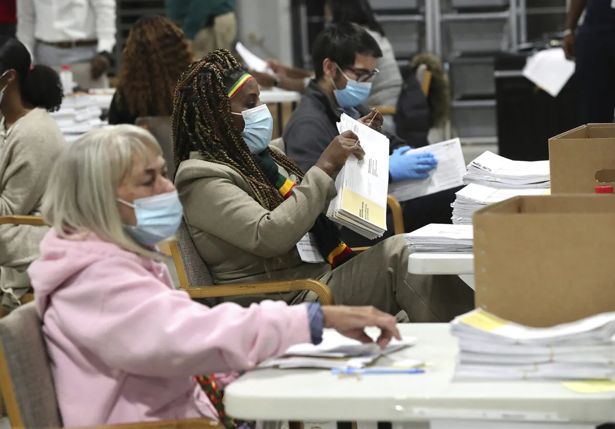 Election workers check-in, sort, and signature verify absentee ballots for the state's U.S. Senate runoff election at the Beauty P. Baldwin Voter Registrations and Elections Building on Tuesday night, Jan. 5, 2021, in Lawrenceville, Ga. (Curtis Compton/Atlanta Journal-Constitution via AP)