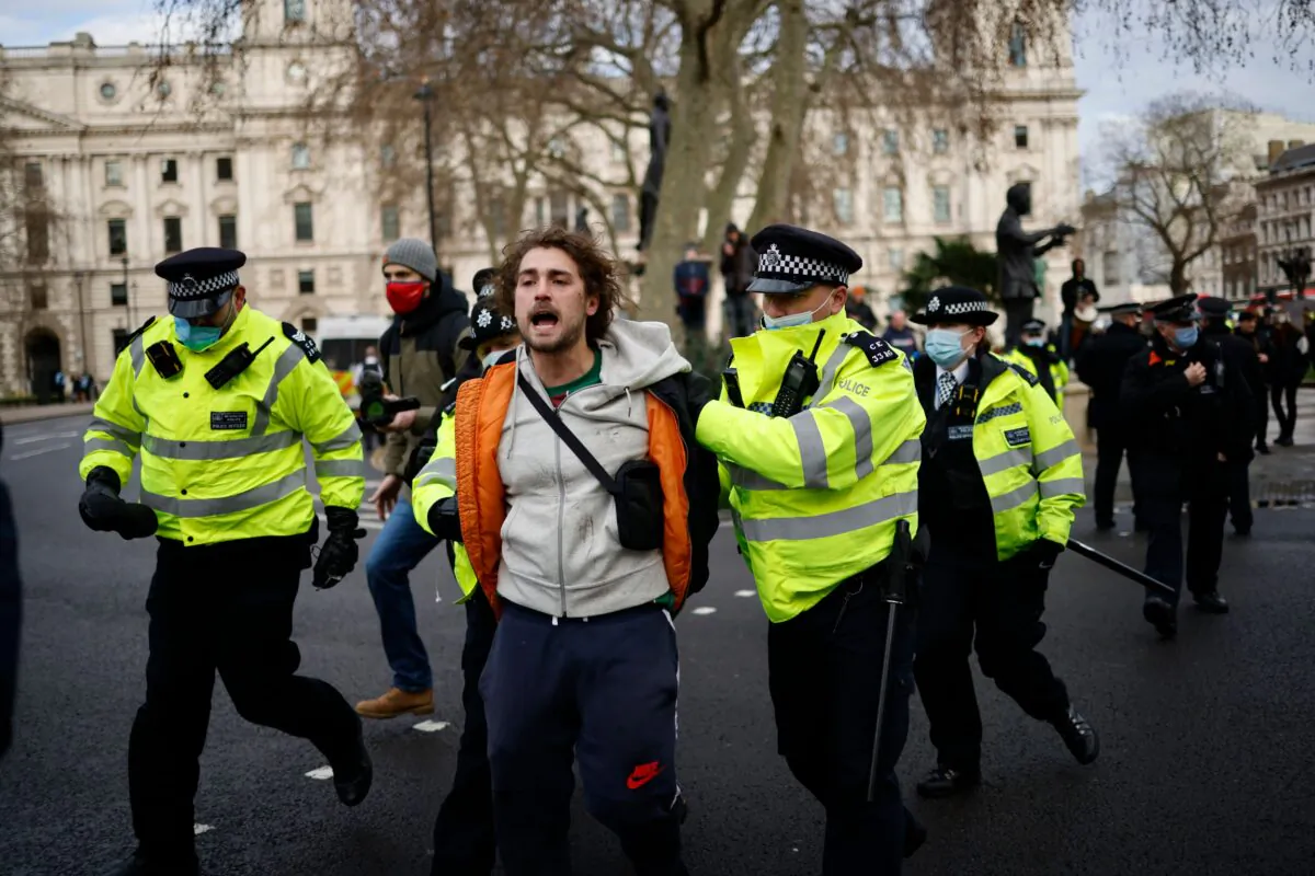 Police officers arrest a protester during an anti-CCP virus lockdown demonstration outside the Houses of Parliament in Westminster, central London, on Jan. 6, 2021. (Tolga Akmen/AFP via Getty Images) 