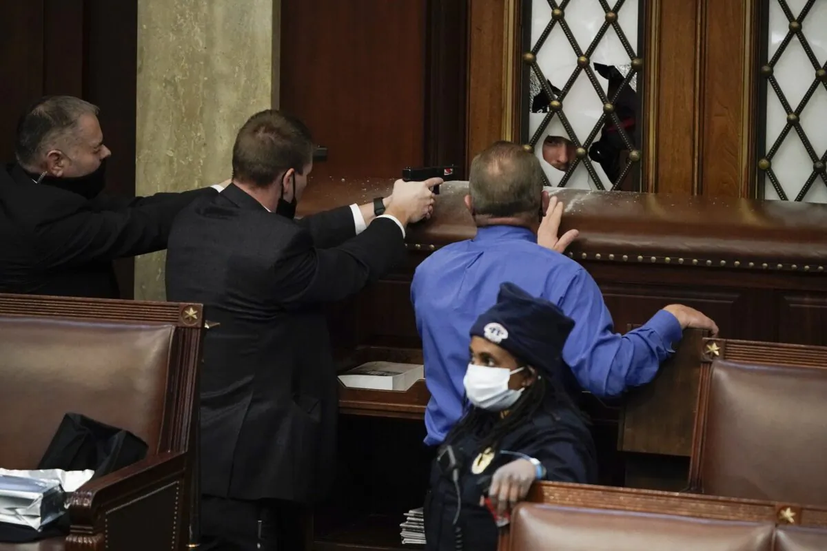 Police with guns drawn watch as protesters try to break into the House Chamber at the U.S. Capitol in Washington on Jan. 6, 2021. (J. Scott Applewhite/AP Photo)