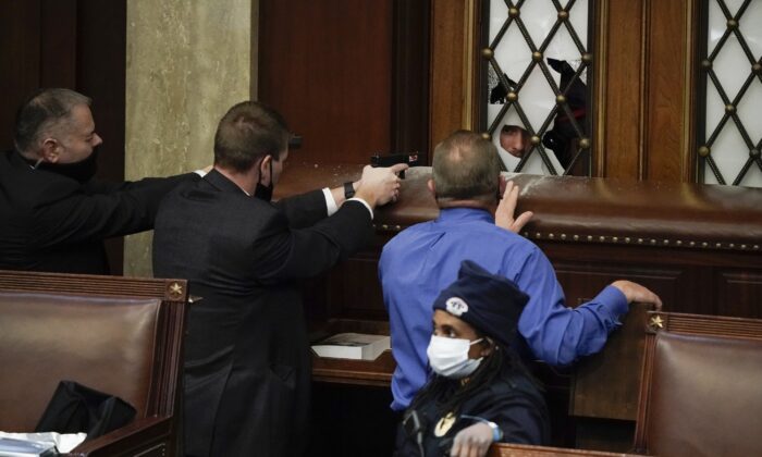 Police with guns drawn watch as protesters try to break into the House Chamber at the U.S. Capitol in Washington on Jan. 6, 2021. (J. Scott Applewhite/AP Photo)