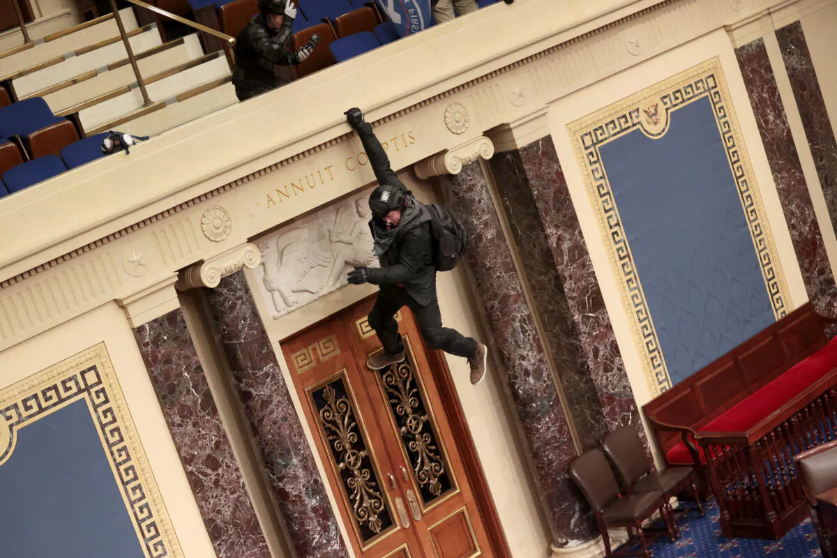 A protester is seen hanging from the balcony in the Senate Chamber in Washington on Jan. 6, 2021. (Win McNamee/Getty Images)