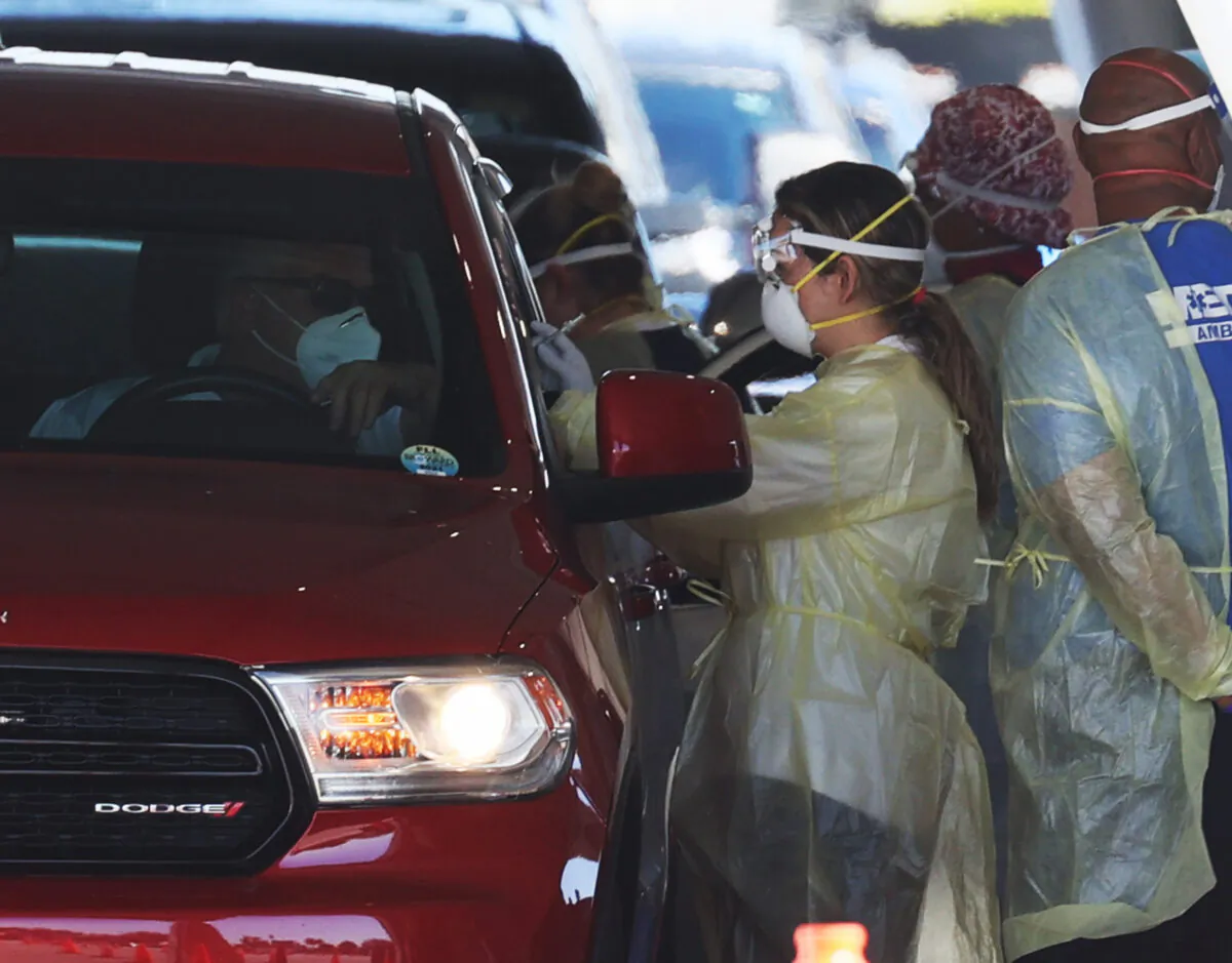 Health care workers administer a COVID-19 vaccination to people at a drive thru site at the Hard Rock Stadium in Miami Gardens, Fla., on Jan. 6, 2021. (Joe Raedle/Getty Images)