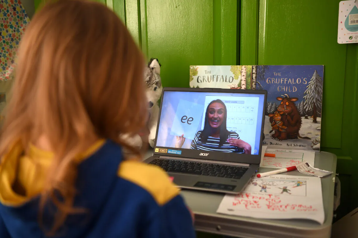A five-year-old girl watches an online phonics lesson on a laptop in her bedroom on the second day of the nationwide school closures in Newcastle-under-Lyme, England, on Jan. 6, 2021. (Gareth Copley/Getty Images)