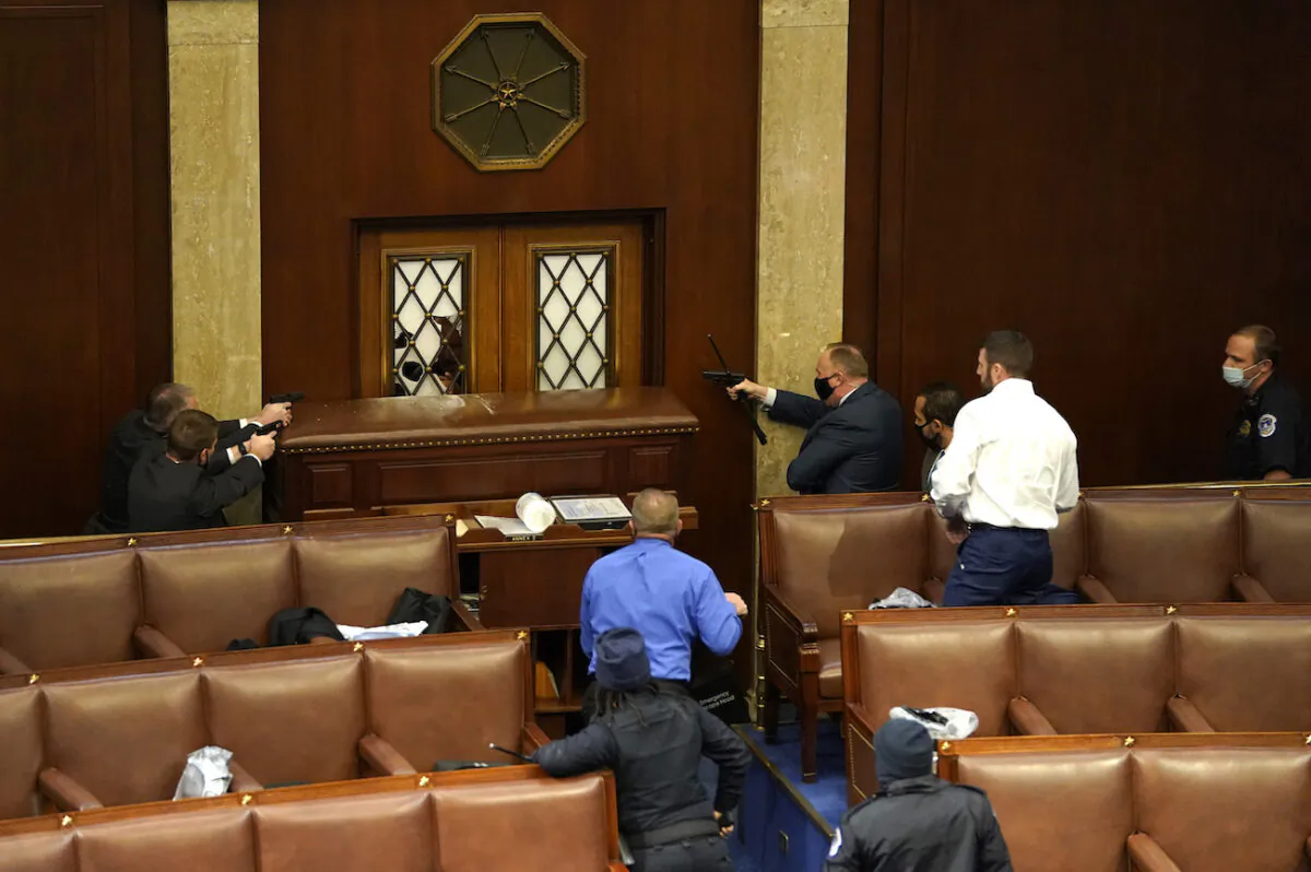Law enforcement officers point their guns at a door that was vandalized in the House Chamber during a joint session of Congress in Washington, on Jan. 6, 2021. (Drew Angerer/Getty Images)