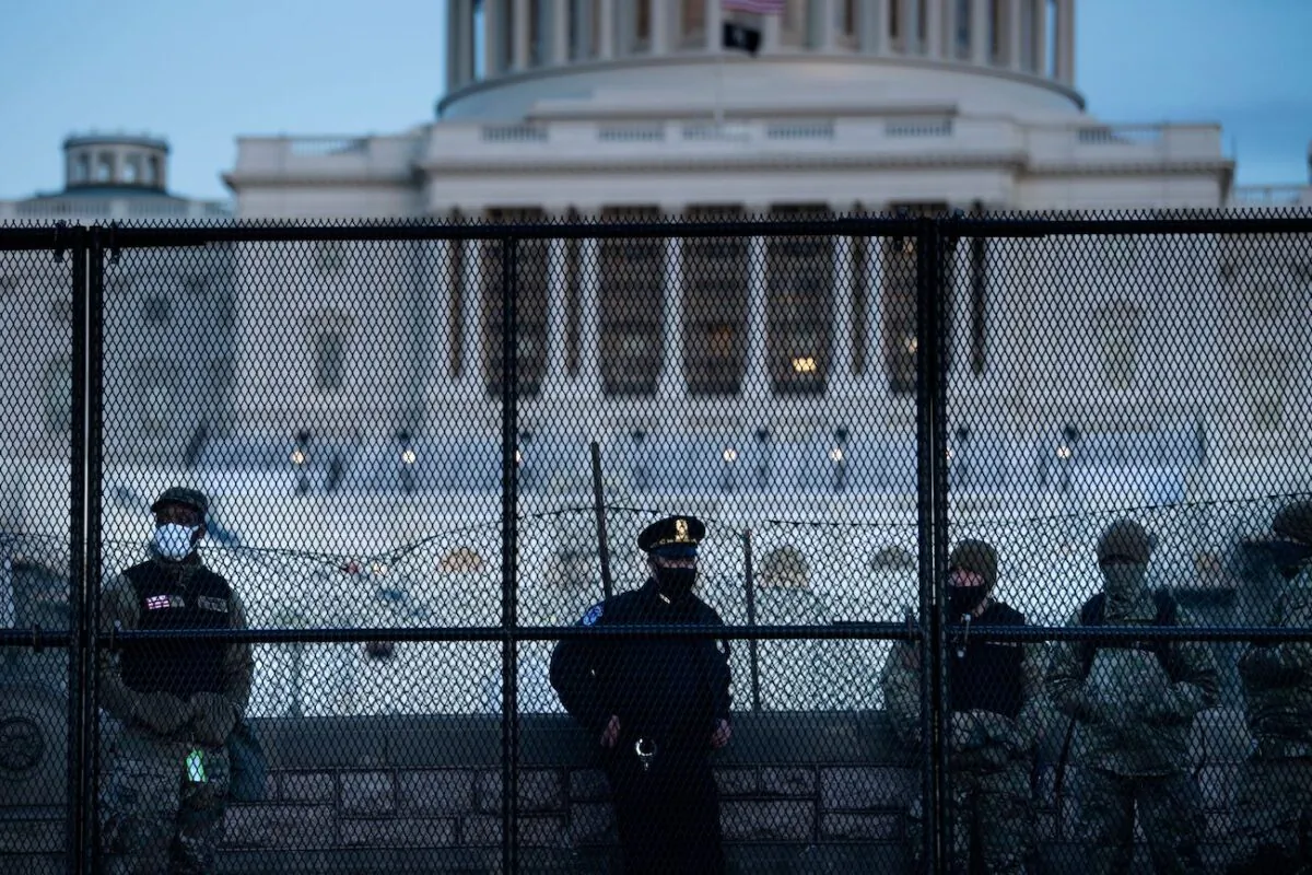 A Capitol Police officer stands with members of the National Guard behind a crowd control fence surrounding Capitol Hill a day after a group broke into the U.S. Capitol in Washington, on Jan. 7, 2021. (Brendan Smialowski/AFP via Getty Images)