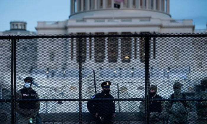 A Capitol Police officer stands with members of the National Guard behind a crowd control fence surrounding Capitol Hill a day after a group broke into the U.S. Capitol in Washington, on Jan. 7, 2021. (Brendan Smialowski/AFP via Getty Images)