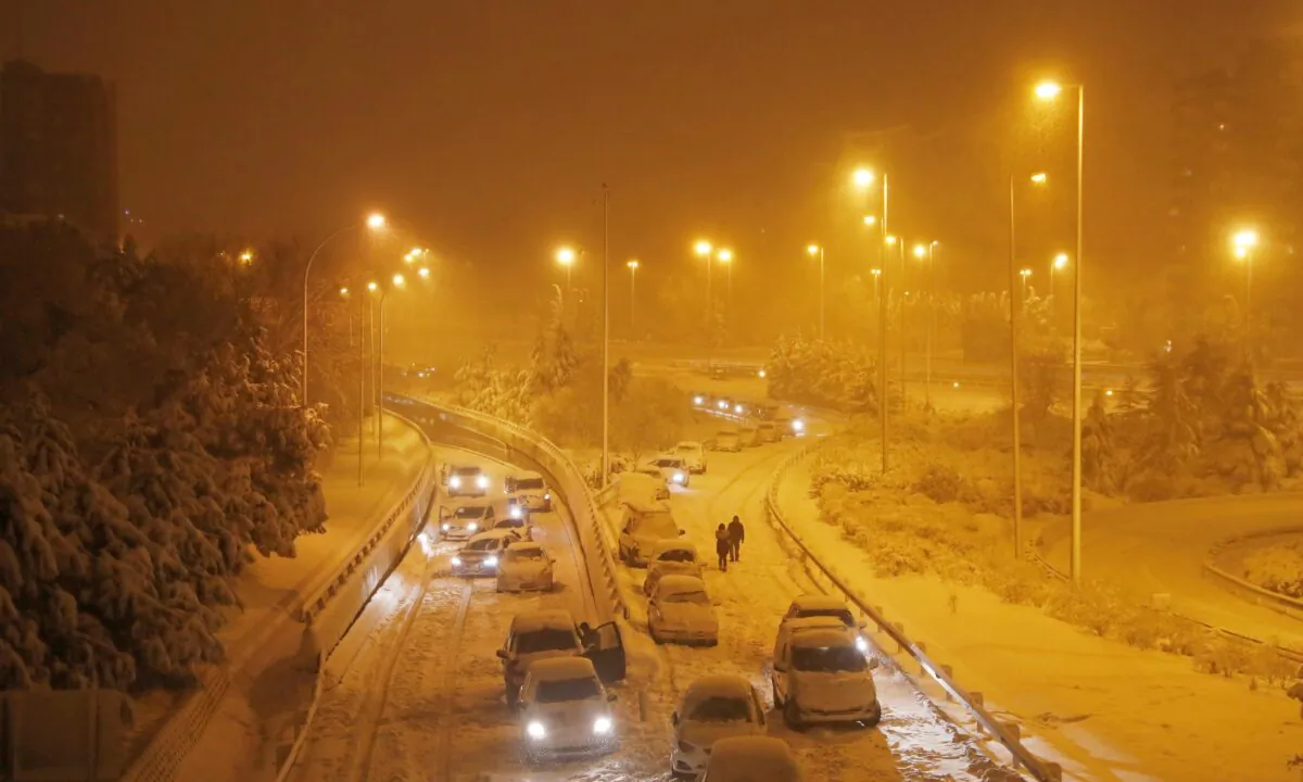 People walk after leaving their vehicles on an access road to the M-30 motorway during a heavy snowfall in Madrid, Spain, on Jan. 9, 2021. (Susana Vera/Reuters)