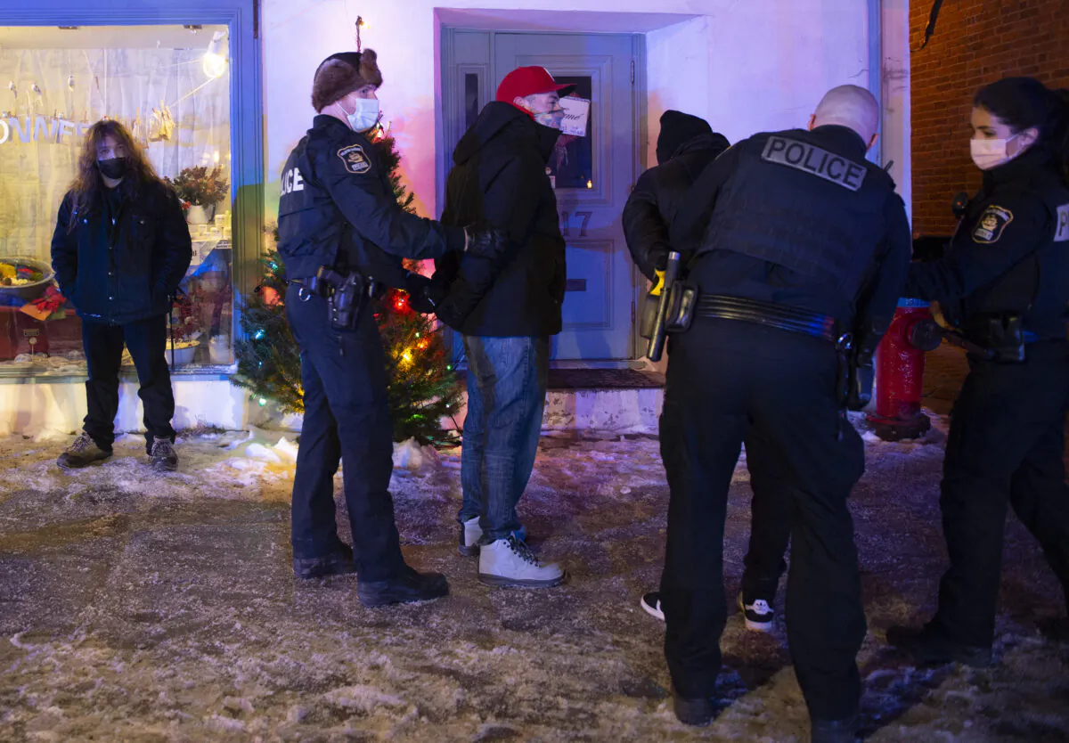 Police arrest two men in Quebec City for breaking a new curfew in the province of Quebec, Canada, on Jan. 9, 2021. (Jacques Boissinot/The Canadian Press)