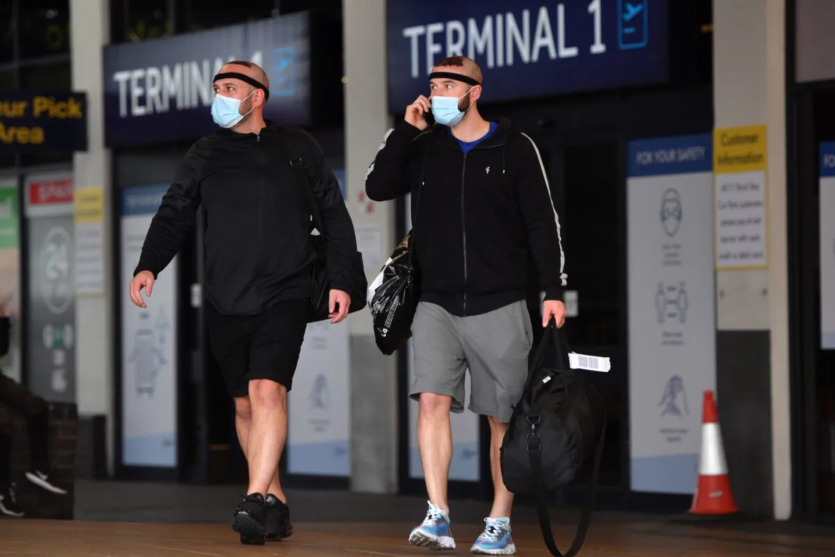 Passengers wearing a face mask or covering due to the COVID-19 pandemic, react as they exit Terminal 1 after landing at Manchester Airport, northwest England, on July 27, 2020. (Anthony Devlin/AFP via Getty Images)