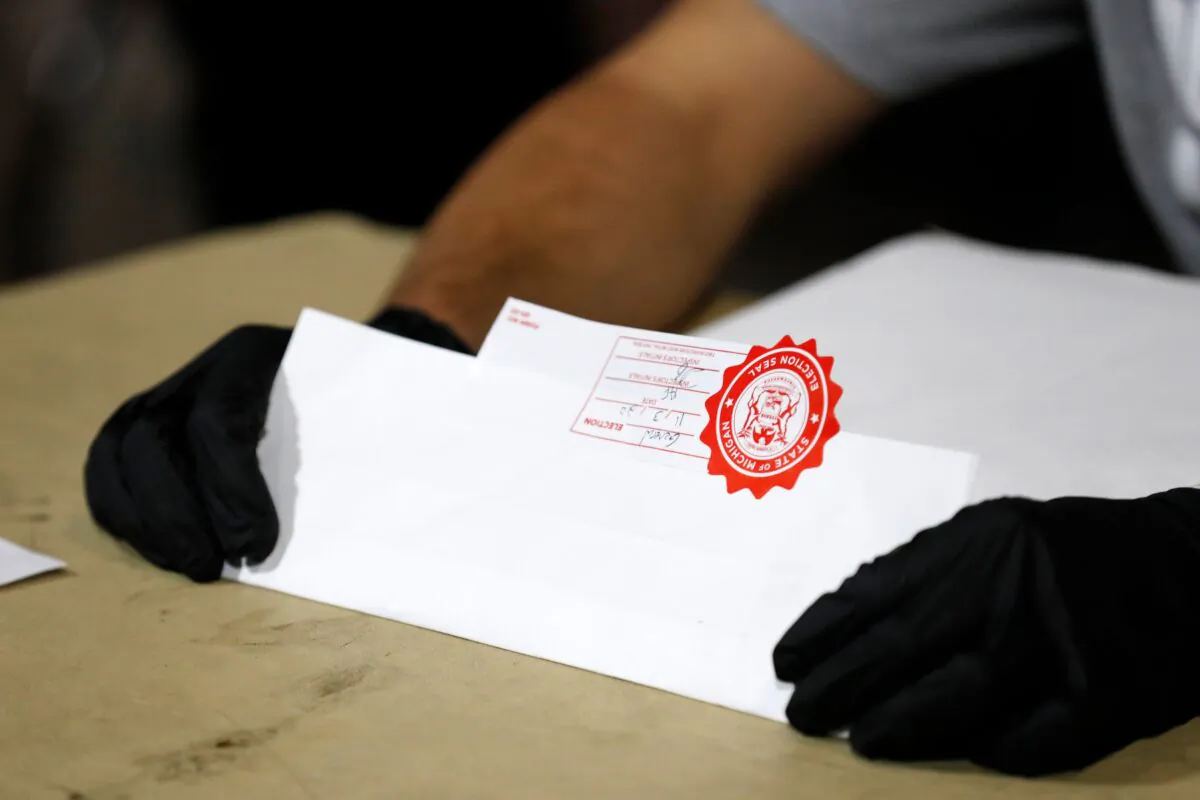 Election workers check the tapes from the voting machines to verify they contain the correct signatures from polling stations after polls closed in the general election at Ford Field in Detroit, Mich., on Nov. 3, 2020. (Jeff Kowalsky/AFP via Getty Images)