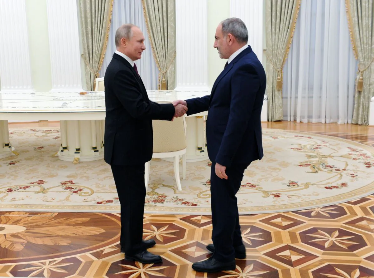 Russian President Vladimir Putin (L) shakes hands with Armenian Prime Minister Nikol Pashinyan before a meeting with leaders of Armenia and Azerbaijan over the disputed Nagorno-Karabakh region's future at the Kremlin in Moscow on Jan. 11, 2021. (Mikhail Klimentyev/SPUTNIK/AFP via Getty Images)