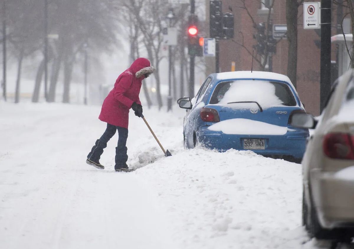 A woman shovels snow away from her car during the first heavy snowfall of the season in Montreal, Canada on Jan. 2, 2021. (Graham Hughes/The Canadian Press)