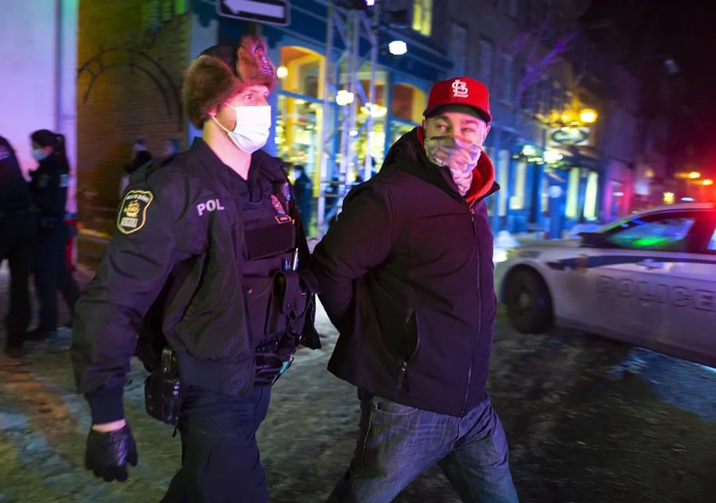 A man is arrested by police after 8 p.m. as a curfew begins in the province of Quebec to counter the spread of COVID-19 on Jan. 9, 2021 in Quebec City. (Jacques Boissino/The Canadian Press)