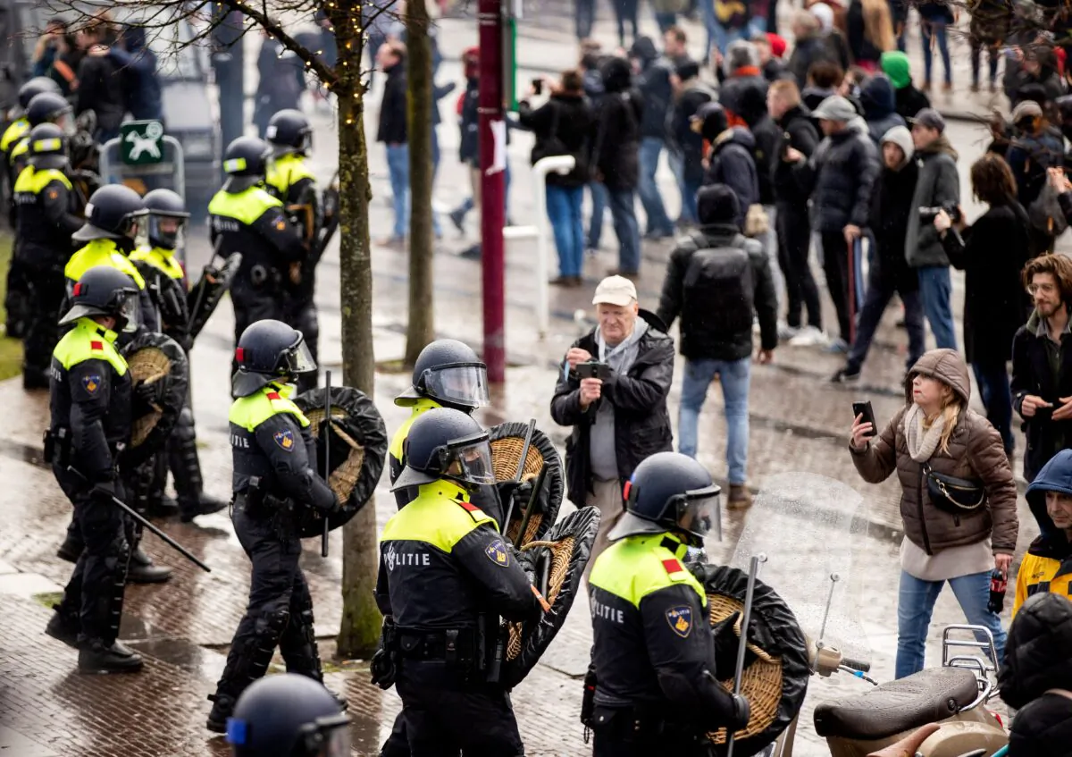 Dutch riot police stand near anti-government activists as they denounce ongoing restrictions related to the coronavirus disease (COVID-19) pandemic among other issues in Museumplein, Amsterdam, on Jan. 17, 2021. (Robin van Lonkhuijsen/ANP/AFP via Getty Images)