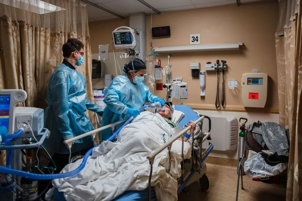 Health care workers use a continuous positive airway pressure machine on a COVID-19 patient who was having difficulties breathing, in a COVID-19 holding pod at Providence St. Mary Medical Center in Apple Valley, Calif., on Jan. 11, 2021.  (Ariana Drehsler/AFP via Getty Images)