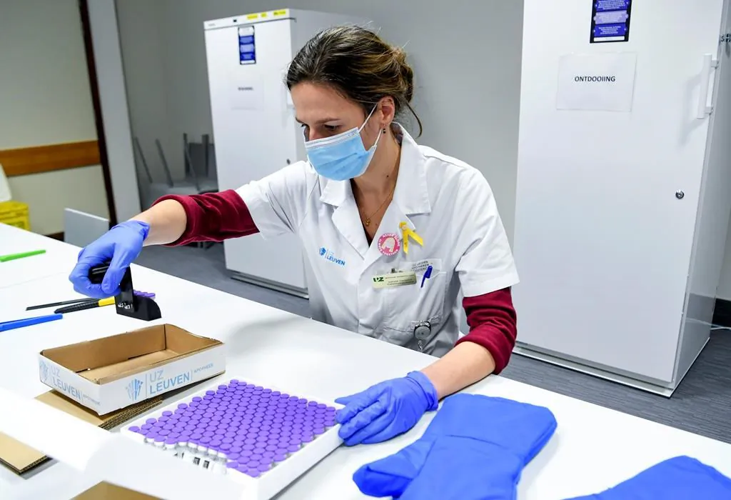 A health worker inspects vials of the Pfizer-BioNTech COVID-19 vaccine as they are thawed in a lab at the UZ Leuven hospital in Leuven, Belgium, on Dec. 27, 2020. (The Canadian Press/Frederic Sierakowski, Pool via AP)