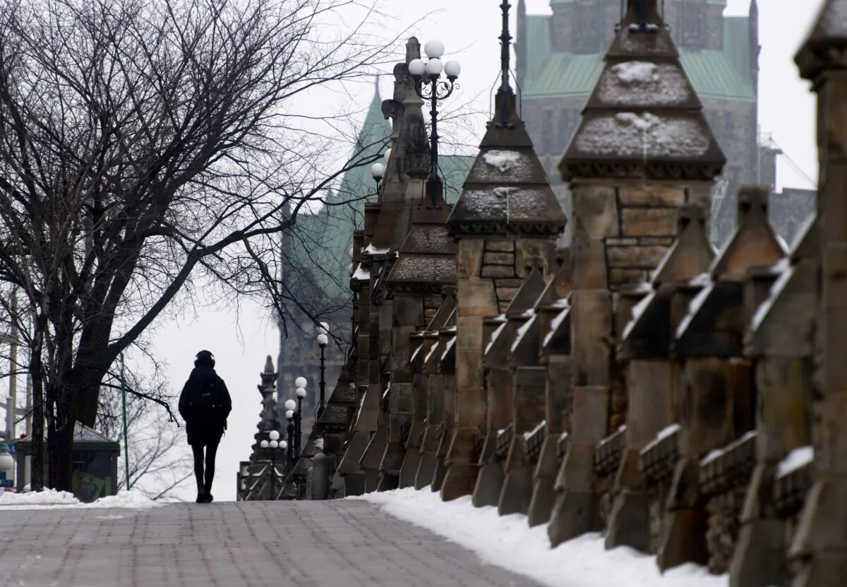 A person walks along the sidewalk next to Parliament Hill in Ottawa on Jan. 14, 2021. (The Canadian Press/Adrian Wyld)