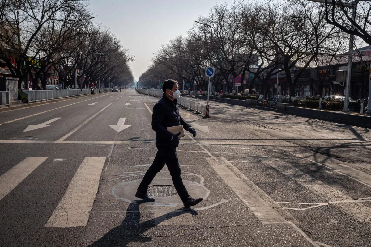 A man wearing a protective mask and gloves walks on a nearly empty street in Beijing on Feb. 23, 2020. (Nicolas Asfouri/AFP via Getty Images)