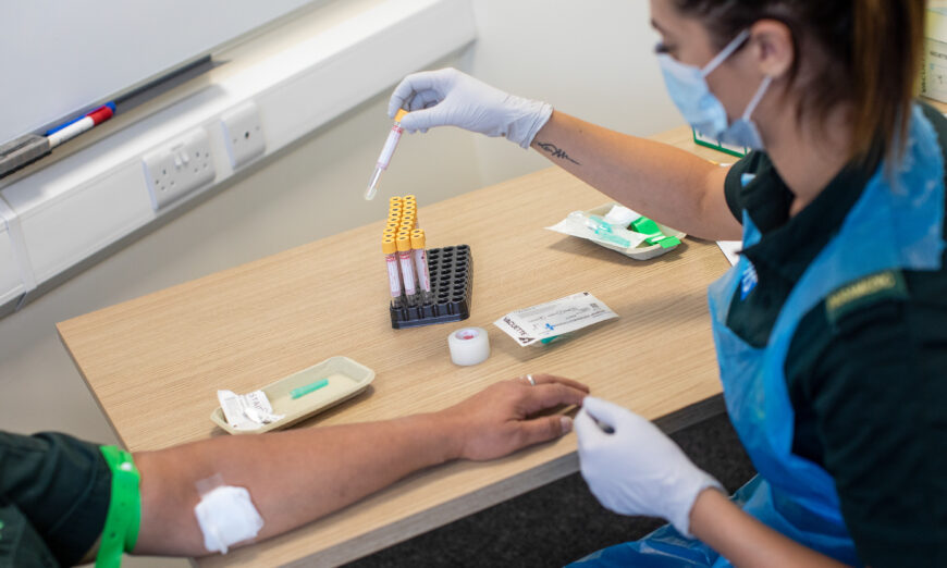 A paramedic, right, holds a test tube to be used for a blood sample during an antibody testing program  operated by the West Midlands Ambulance Service NHS Foundation Trust, in Birmingham, England, on June 5, 2020. (Simon Dawson/Getty Images)