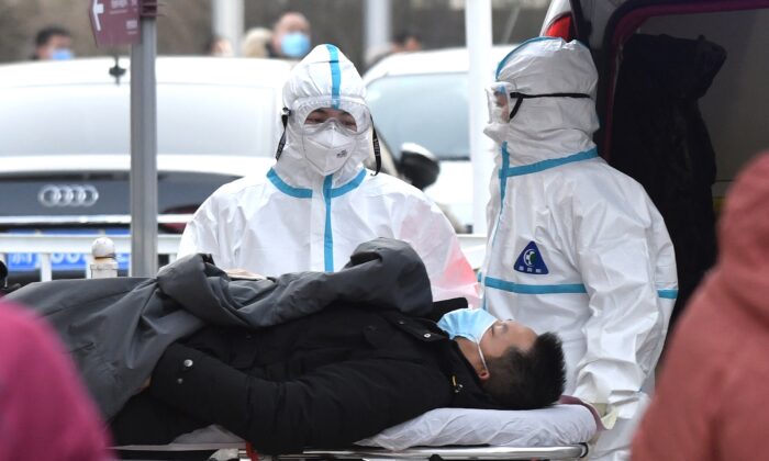 Medical workers wearing protective suits as a precaution against the CCP virus coronavirus deliver a patient to the fever clinic at a hospital in Beijing on Jan. 13, 2021. (GREG BAKER/AFP via Getty Images)